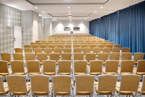 an empty lecture hall with rows of chairs in a room at Holiday Inn Düsseldorf City – Toulouser Allee by IHG in Düsseldorf