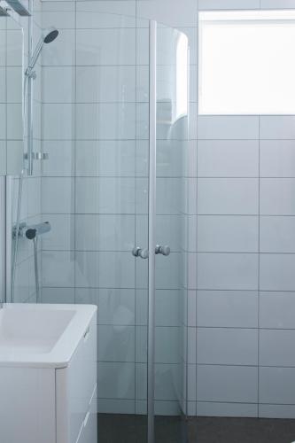 a bathroom with a glass shower and a sink at Sköna Hönor Apartments in Visby