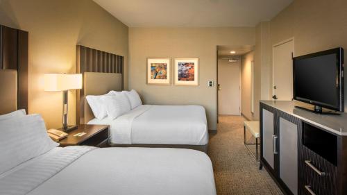 a hotel room with two beds and a flat screen tv at Holiday Inn Denver Lakewood by IHG in Lakewood