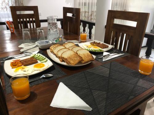 a table with two plates of food and orange juice at Kandyan Lounge in Kiribatkumbura