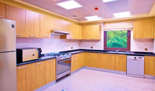 a kitchen with wooden cabinets and a white refrigerator at Apartment 004 - Mina Al Fajer in Fujairah