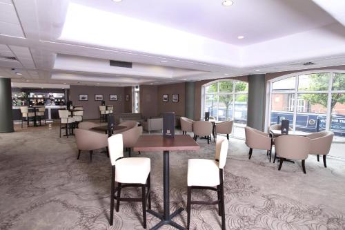 a dining room with tables and chairs and windows at Holiday Inn Ellesmere Port/Cheshire Oaks by IHG in Ellesmere Port