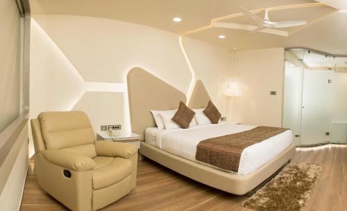 1 dormitorio con 1 cama y 1 silla en Ramyas Hotels, en Tiruchchirāppalli
