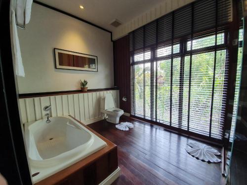a bathroom with a large tub and a toilet at Le Palais Juliana in Luang Prabang