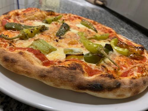 eine Pizza auf einem weißen Teller auf einem Tisch in der Unterkunft Hotel Pizzeria Da Beni in Kochersteinsfeld