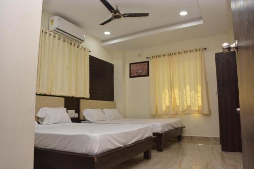 a bedroom with two beds and a ceiling fan at Arihanth Inn in Vellore