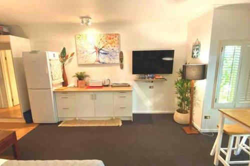 a living room with a white refrigerator and a flat screen tv at Ramada Resort - Stylish Deluxe Apartment in Port Douglas