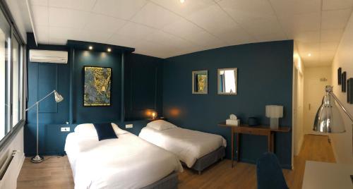 a bedroom with two beds and a blue wall at Logis Hôtel l'Abricotine in Tain-lʼHermitage