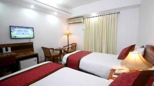 a hotel room with two beds and a television at Hotel Victory - Best in City Center in Dhaka