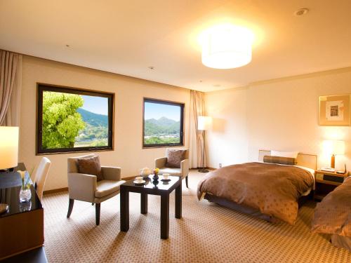 岐阜市にある長良川清流ホテルのベッド、テーブル、椅子が備わるホテルルームです。