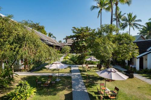 a garden with tables and chairs and umbrellas at Sanctuary Hotel Luang Prabang in Luang Prabang