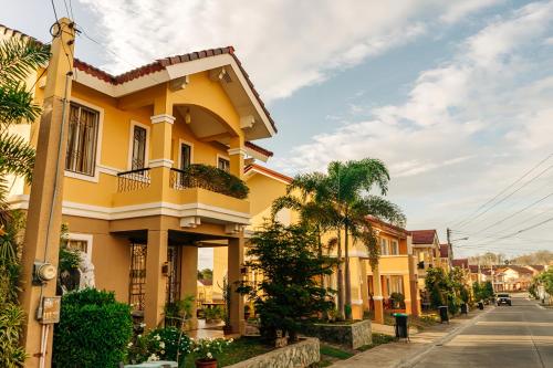 a yellow house on a street with palm trees at Perfect staycation for families, friends, business travelers and tourist in Calacapan