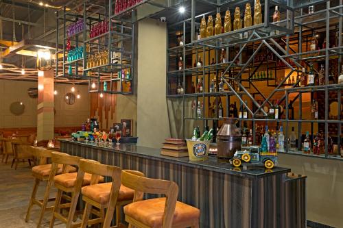 a bar with wooden stools and bottles of alcohol at Regenta Central Cassia Zirakpur Chandigarh in Chandīgarh