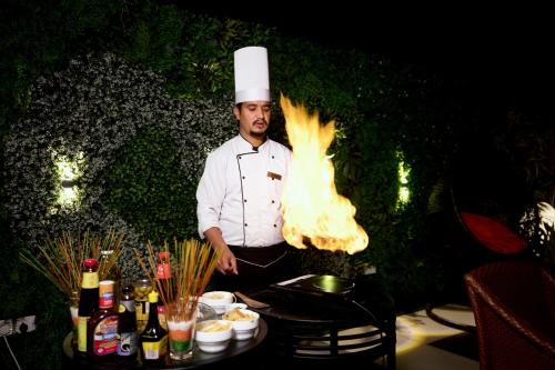 a chef is standing next to a table with a fire at Regenta Central Cassia Zirakpur Chandigarh in Chandīgarh