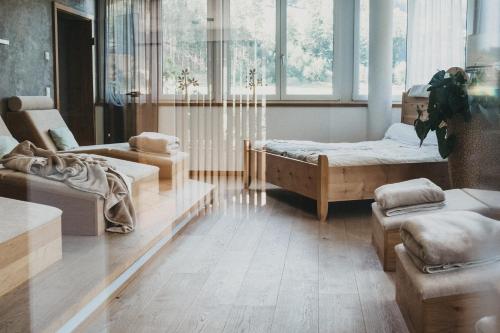 a room with two beds and a chair and a couch at Biohotel Rupertus in Leogang