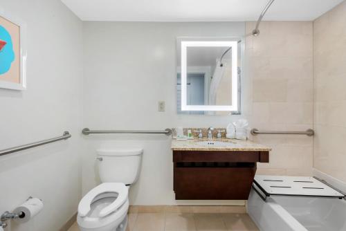a bathroom with a toilet and a sink and a mirror at Holiday Inn Orlando – Disney Springs® Area by IHG in Orlando