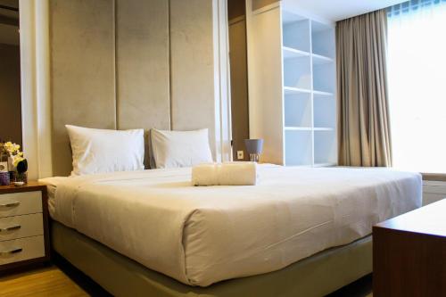 a bedroom with a large white bed with a window at Stunning 3BR Apartment at The Branz BSD City By Travelio in Samporo