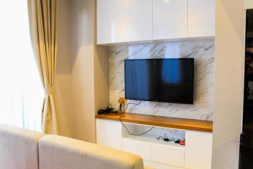 a living room with a tv on a marble wall at Stunning 3BR Apartment at The Branz BSD City By Travelio in Samporo