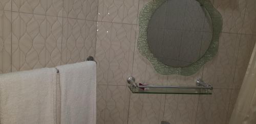 a bathroom with a mirror and two towels at Hotel Oasis in Morogoro