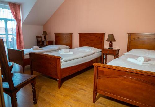 1 dormitorio con 3 camas, muebles de madera y ventana en Hotel Lony, en Mochov