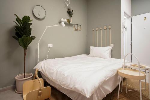 a bedroom with a white bed and a table and a plant at Jerusalem market apartment in Jerusalem