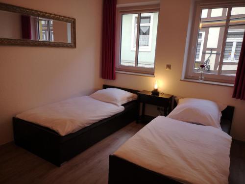 two beds in a room with two windows at Haus der Harmonie in Hameln
