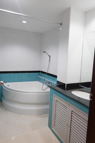 a bathroom with a tub and a sink at Auychai Grand Hotel in Lang Suan
