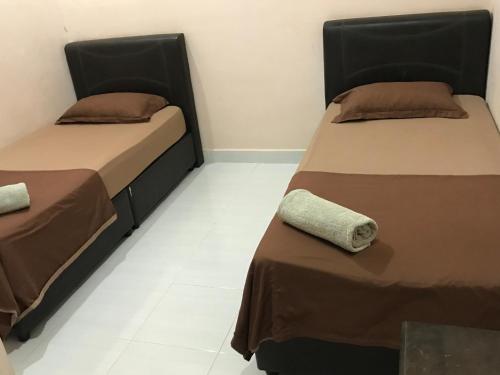 two beds sitting next to each other in a room at Malinja Homestay in Kuah