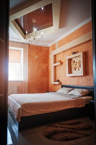 a bedroom with orange walls and a bed with a chandelier at Avto Spa in Khmelʼnytsʼkyy