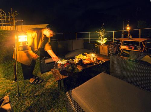 a woman standing on a patio at night with a table at -Musée Villa- in Nakijin