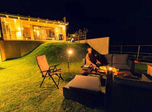 a man sitting on a couch in a yard at night at -Musée Villa- in Nakijin