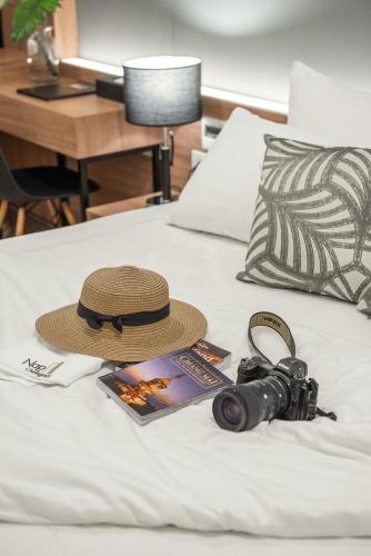 a hat and a camera and a magazine on a bed at Nap in Chiangmai in Chiang Mai