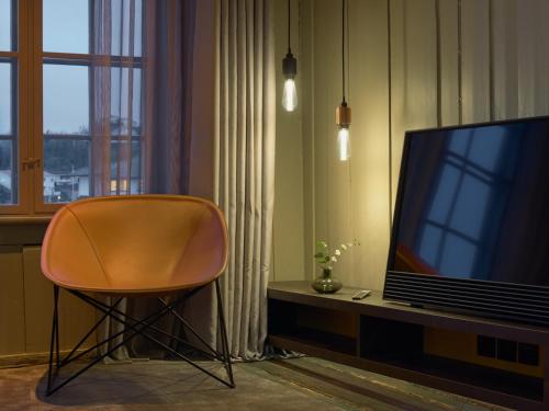 a chair sitting next to a television in a room at Tollboden Hotell - Unike Hoteller in Kragerø