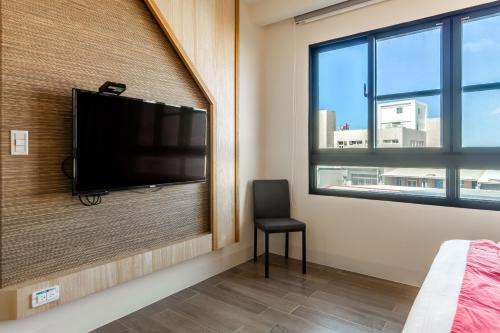 a bedroom with a flat screen tv on a wall at Mambo Boutique Hotel in Hengchun