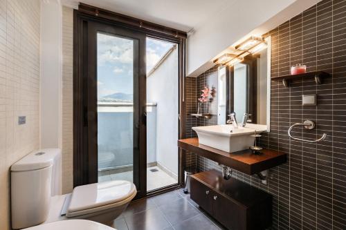 a bathroom with a sink and a toilet and a window at Melon Suites in Thessaloniki