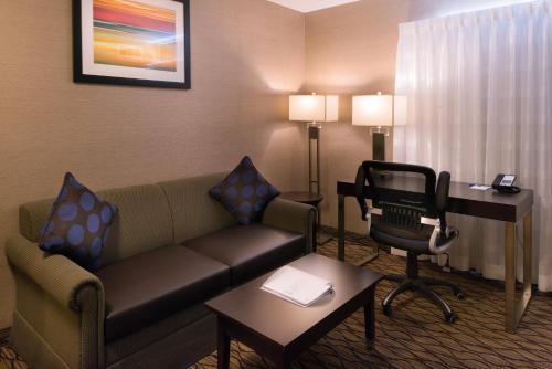 a living room with a couch and a desk in a hotel room at Holiday Inn Express & Suites Pasadena - Los Angeles by IHG in Pasadena