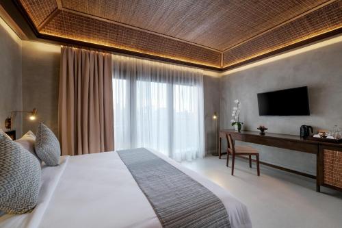 a bedroom with a bed and a desk with a television at The Garcia Ubud Hotel & Resort in Ubud