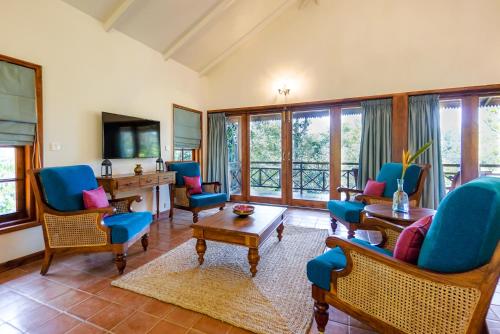 a living room with blue chairs and a desk at Pepper Trail in Sultan Bathery