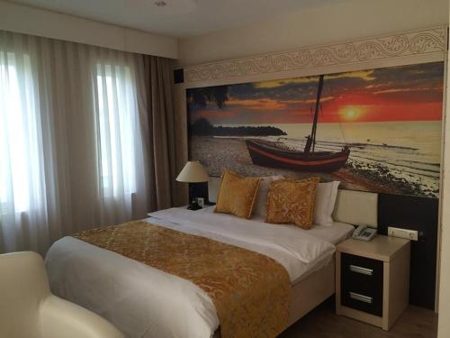 a bedroom with a bed and a painting of a boat at Rumana Hotel in Anamur