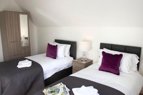 two beds in a hotel room with purple pillows at Flower In Hand Apartment in Norwich