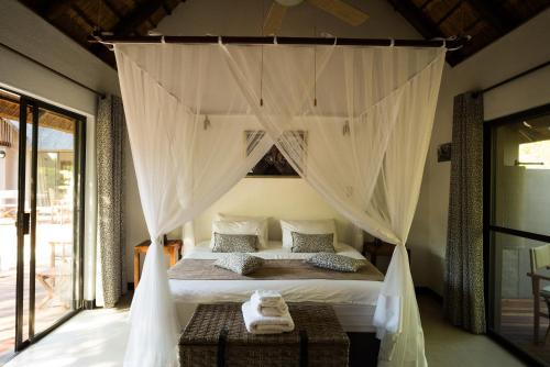 a bedroom with a canopy bed with curtains at Swiblati Lodge in Hoedspruit