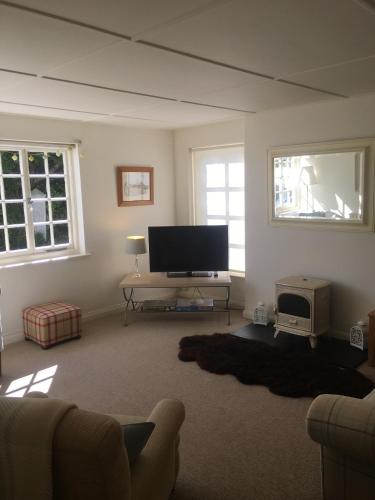 a living room with a flat screen tv and a couch at The Thatched Cottage in Truro