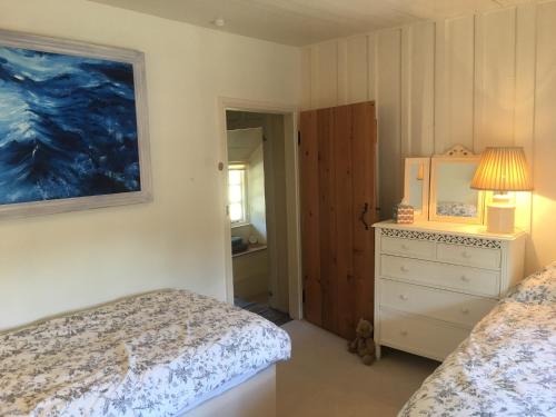 a bedroom with two beds and a dresser with a lamp at The Thatched Cottage in Truro