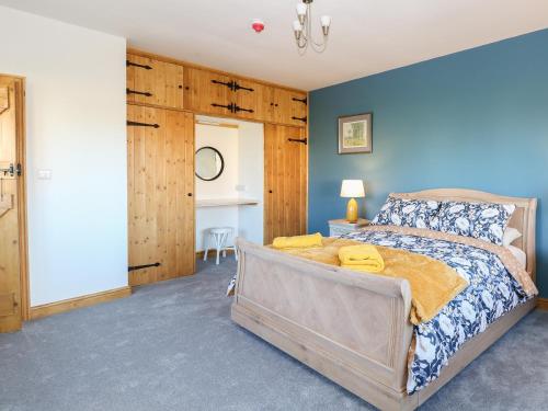 a bedroom with a large bed and blue walls at 1 Stud Cottage in Norwich