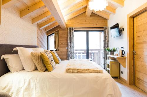 - une chambre avec un grand lit blanc et des plafonds en bois dans l'établissement Chalet sur les monts Morzine, à Montriond