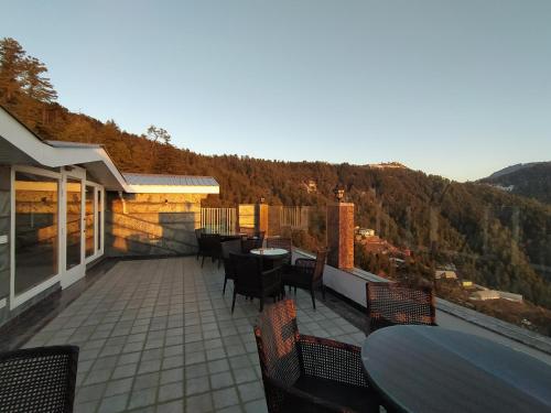 a patio with tables and chairs on a balcony at The Retreat Mashobra, Shimla in Shimla