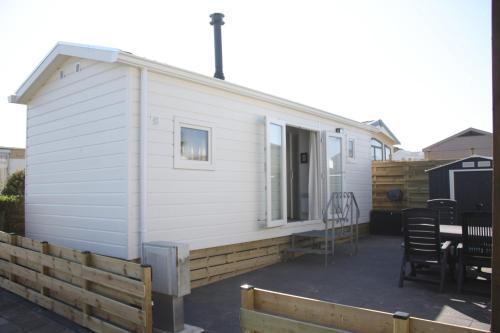 a small white house with a table and chairs at Chalet Charlee in IJmuiden