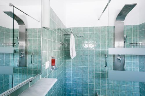 a blue tiled bathroom with a shower and a sink at Spiti Prifti Apartments in Gouvia