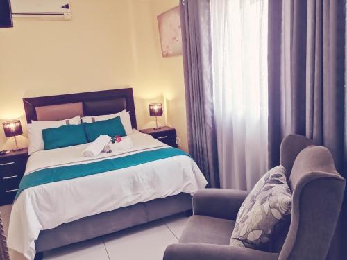 een slaapkamer met een bed en 2 stoelen bij Hilton Gardens Guesthouse in Richards Bay