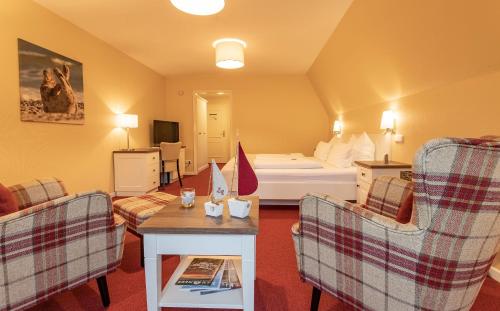 una camera d'albergo con un letto e due sedie di Hotel Landhaus Ellerbrock a Sankt Peter-Ording